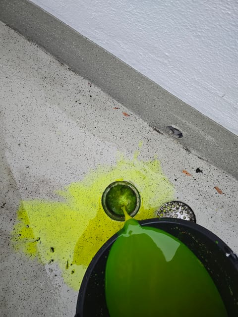 Farbmittelprüfung mit fluoreszierendem grünem Prüfmittel an einem Bodenablauf