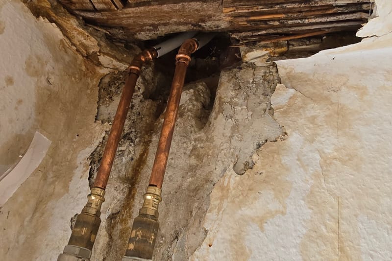 Geöffnete Decke mit freigelegten Wasserleitungen nach einem Wasserschaden
